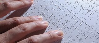Fingertips gliding across page of Braille