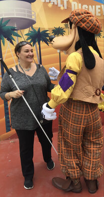 Gina Martin with her cane talking with Pluto while in Disneyland
